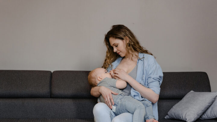 A woman breastfeeding her baby while sitting on the couch