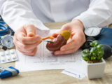 At doctors appointment physician shows to patient shape of kidney with focus on hand with organ. Scene explaining patient causes and localization of diseases of kidney, stones, adrenal, urinary system