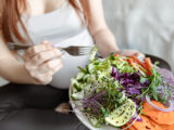 Close-up of a plate with a bright salad of fresh vegetables in the hands of a pregnant woman.